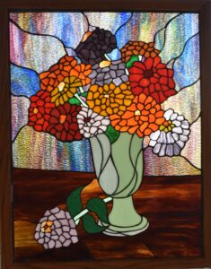 Imagen de una vidriera de un jarrón con flores.